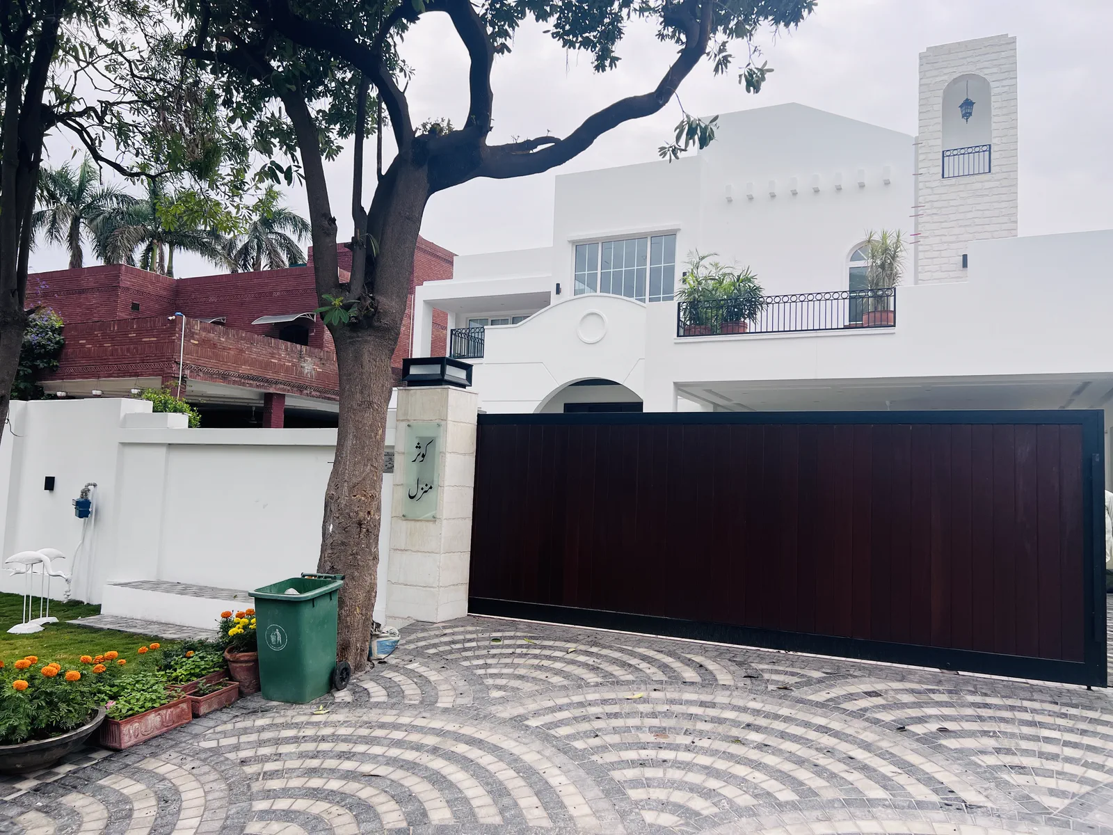 Completed white modern house in Lahore with wooden sliding gate and landscaped entrance